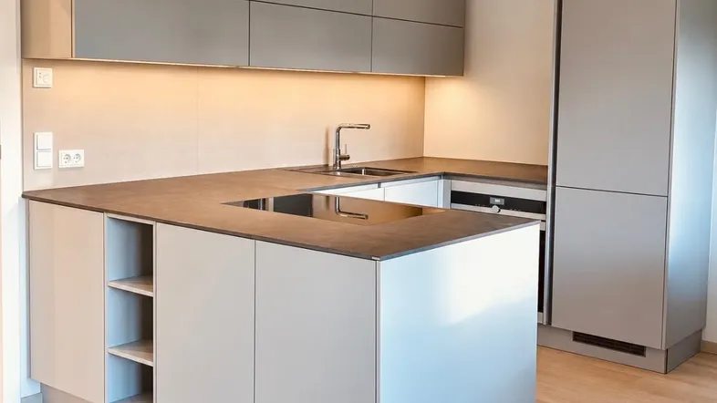 Moderne Küche mit grauen Schränken, integrierten Geräten und Induktionskochfeld in neuwertigem Zustand.