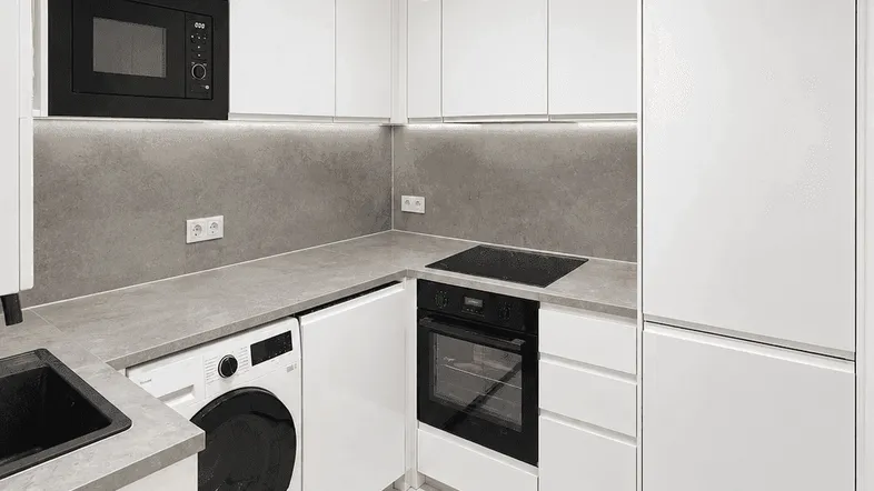 Moderne Küche mit weißen Hochglanzfronten, integrierten Geräten und Waschmaschine, ausgestattet mit Fliesenboden.