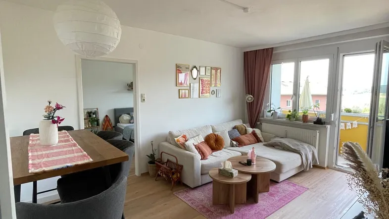 Heller offener Wohnbereich mit Holzboden, gemütlichem Sofa und integriertem Barbereich.