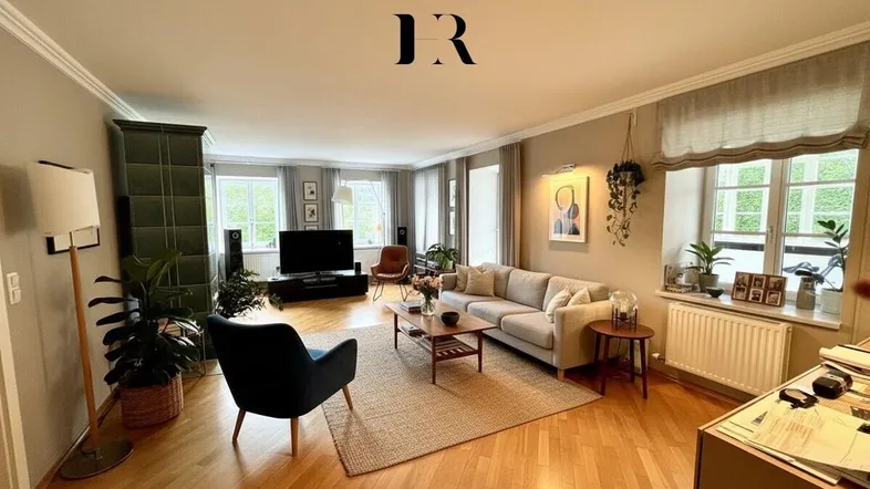 Geräumiges Wohnzimmer mit Parkettboden, Kachelofen und gemütlicher Sitzecke, ideal zum Entspannen.