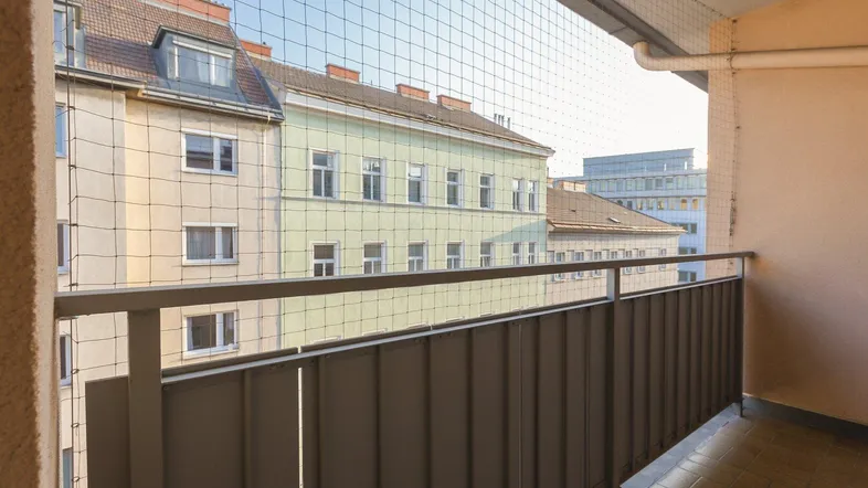 Balkon mit Schutznetz und Blick auf umliegende Gebäude in der Stadt.
