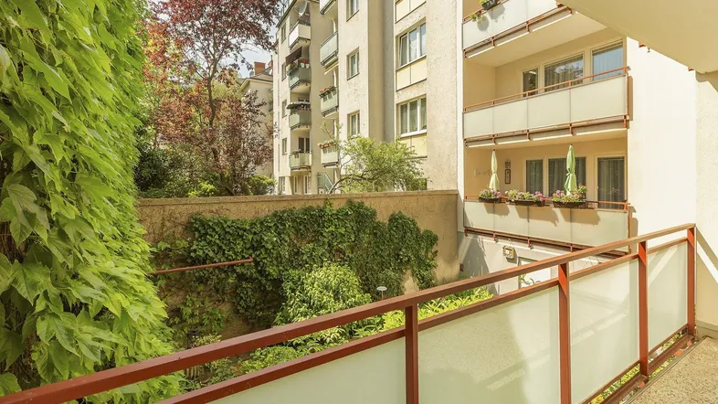 Geräumiger Balkon mit Blick auf begrünte Wände und andere Wohngebäude.