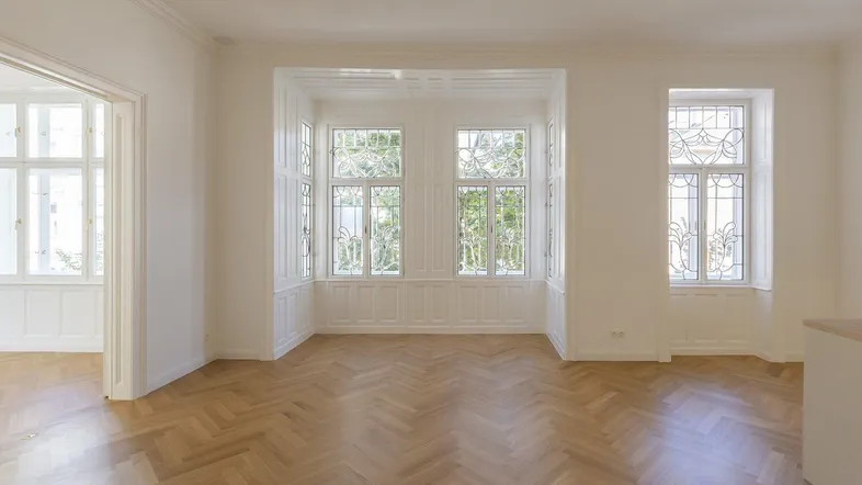 Helles Wohnzimmer mit Fischgrätparkett, hohen Decken und dekorativen Bleiglasfenstern.