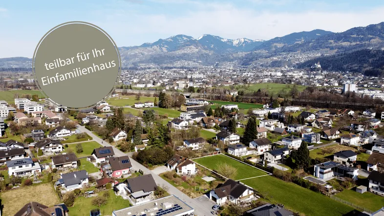 Luftaufnahme eines Baugrundstücks in einer Wohngegend mit Bergpanorama im Hintergrund.