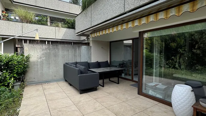 Geräumige Terrasse mit modernen Outdoor-Möbeln und Blick auf die begrünte Fassade des Gebäudes.