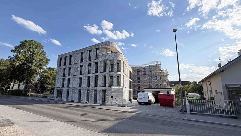 Modernes Gebäude mit grauer Ziegelfassade und geschwungenen Elementen, noch im Bau.