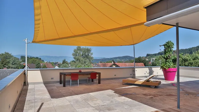 Weitläufige Dachterrasse mit Sonnensegel, Liegestuhl und Essbereich, ideal zum Entspannen.