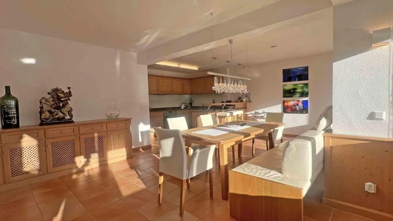 Heller offener Wohn- und Essbereich mit integrierter Küche und traditionellen Holzmöbeln.