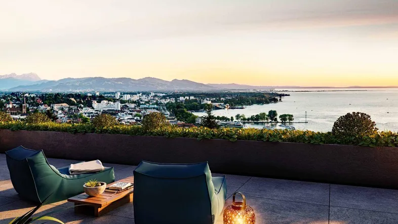 Gemütliche Terrasse mit modernen Sitzmöbeln und atemberaubendem Blick auf den See und die Stadt bei Sonnenuntergang.