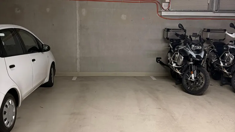 Tiefgaragenstellplatz Nummer 51 mit einem Auto und zwei Motorrädern in einer modernen Tiefgarage.