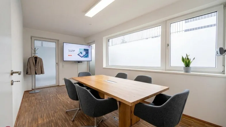 Moderner Konferenzraum mit Holztisch, bequemen Stühlen und einem großen Fenster für natürliches Licht.