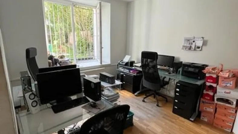 Helles Büro mit zwei Arbeitsplätzen, Holzfußboden und Blick ins Grüne durch das Fenster.