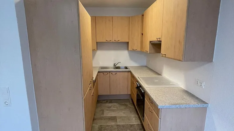 Funktionale Küche mit hellen Holzschränken, Granit-Arbeitsplatte und Fliesenboden.