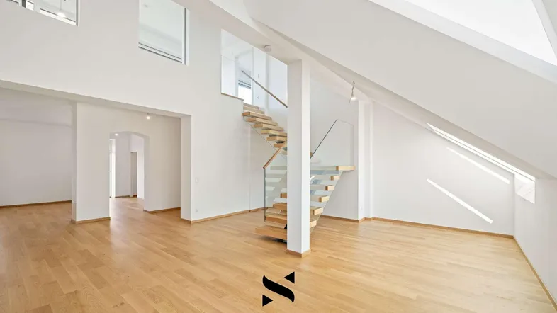 Helles, offenes Wohnzimmer mit Holzparkettboden, moderner Treppe und Dachschrägen.