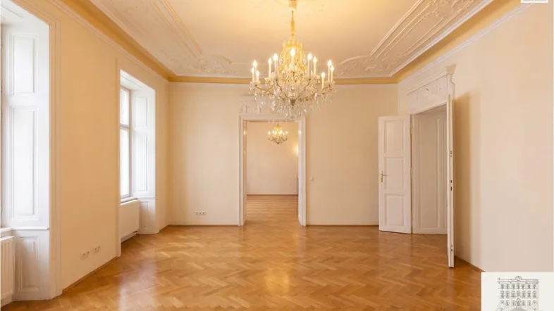 Geräumiges Zimmer mit Fischgrätparkett, hohen Decken und opulentem Kronleuchter.