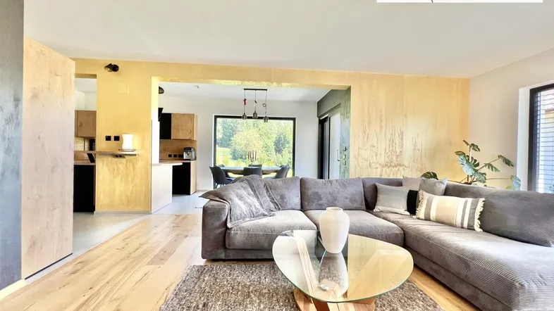 Helles Wohnzimmer mit großem Ecksofa, Holzboden und offener Gestaltung zum Essbereich.