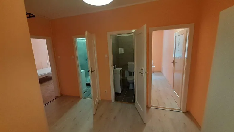 Heller Flur mit orangefarbenen Wänden und mehreren Türen, die zu verschiedenen Räumen führen.
