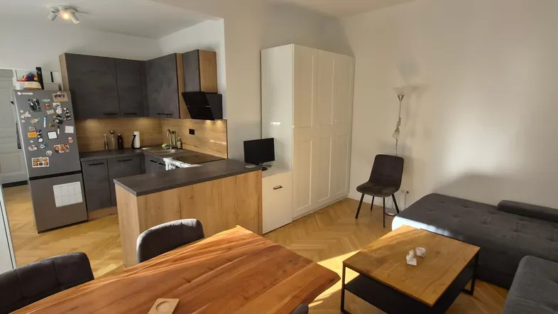 Heller offener Wohn-Essbereich mit moderner Küche, Parkettboden und gemütlichem Sofa.