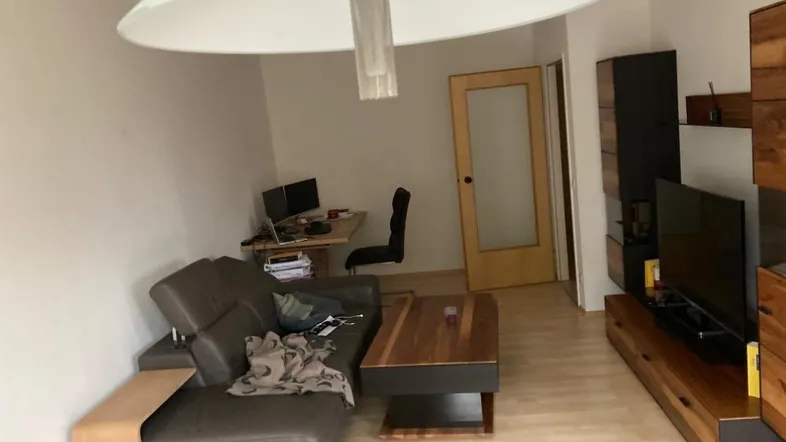 Gemütliches Wohnzimmer mit Sofa, Couchtisch, TV-Möbeln und einem Arbeitsbereich.