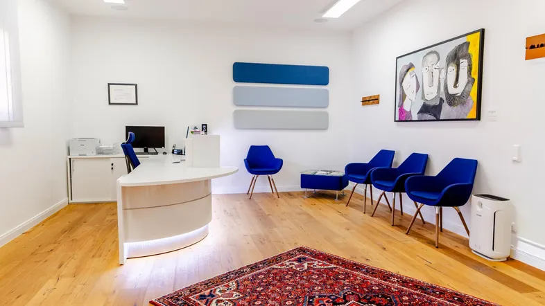 Moderner Empfangsbereich mit Holzboden, blauen Akzenten und Kunstwerken an den weißen Wänden.