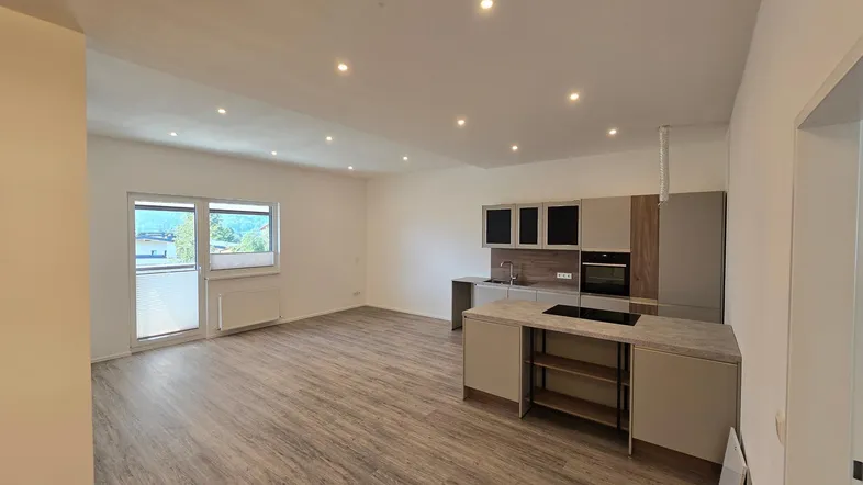 Moderne offene Wohnküche mit Laminatboden, Einbauküche und Blick auf die Berge.