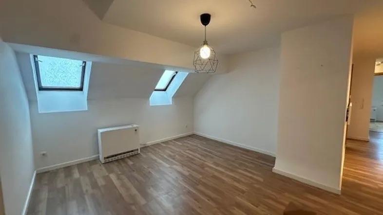 Helles Zimmer im Dachgeschoss mit Holzoptikboden und zwei Dachfenstern, ideal als Schlaf- oder Arbeitszimmer.