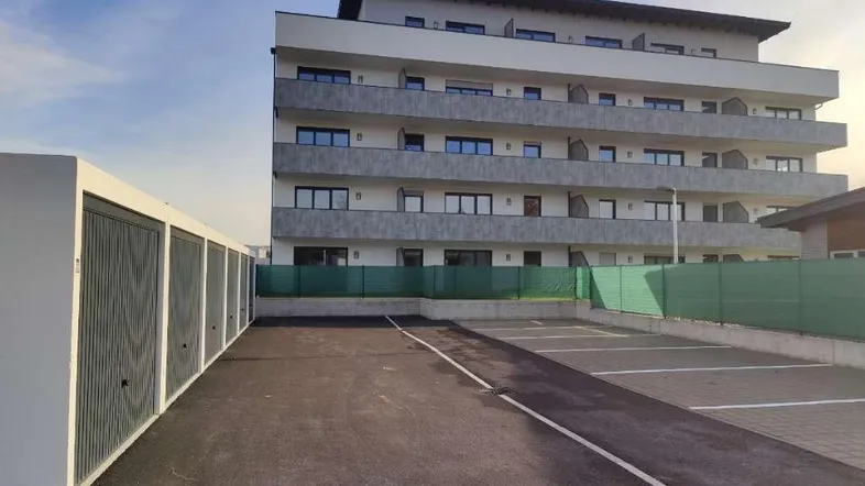 Modernes Mehrfamilienhaus mit Balkonen, Parkplätzen und Garagen in der Außenansicht.