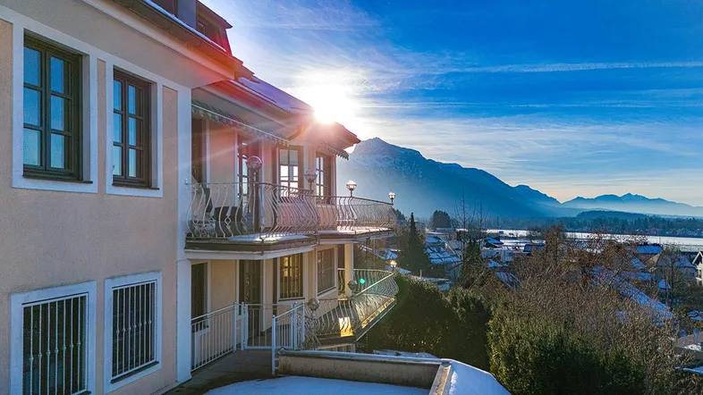 Gebäudeansicht mit mehreren Balkonen und beeindruckendem Bergblick bei Sonnenuntergang.