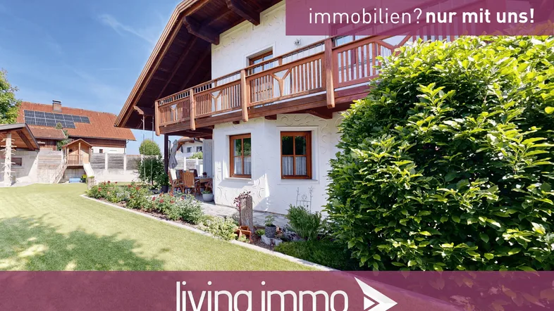 Haus mit traditionellem Holzbalkon, gepflegtem Garten und sonniger Terrasse.