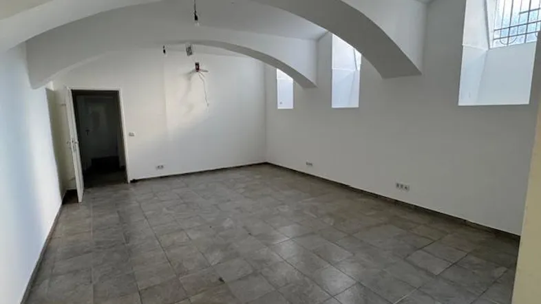 Geräumiger, heller Raum mit Gewölbedecke und Fliesenboden, bereit für die individuelle Gestaltung.
