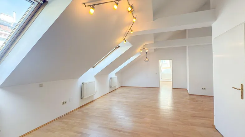 Helles Dachgeschosszimmer mit Holzboden und schrägen Wänden, ideal als Wohnbereich nutzbar.