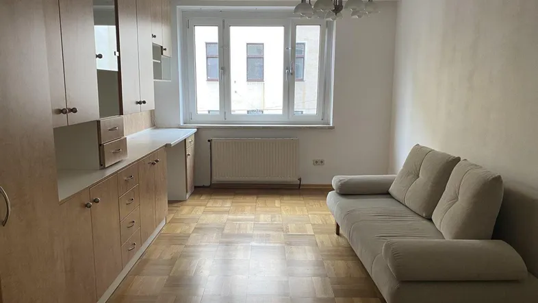 Helles Zimmer mit beigem Sofa, Einbauschränken und Parkettboden, ideal als Wohn- oder Schlafbereich.