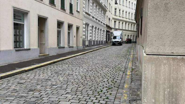Kopfsteingepflasterte Straße mit historischen Gebäuden und klassischer Architektur in einer städtischen Umgebung.