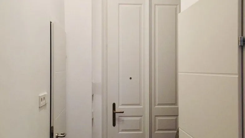 Heller Eingangsbereich mit weißen Türen, dunklem Fliesenboden und einem Heizkörper an der Wand.