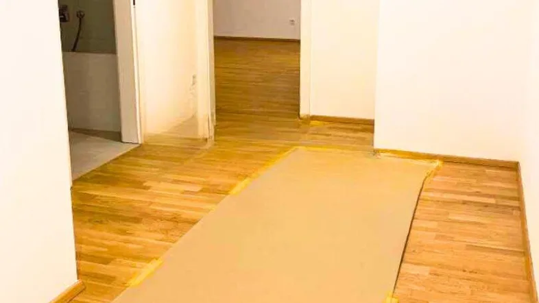 Heller Flur mit Holzparkettboden, der zu einem Badezimmer und einem weiteren Raum führt.