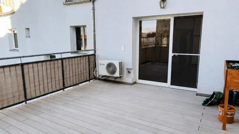 Große Dachterrasse mit modernem Holzdeck und Blick auf umliegende Gebäude.