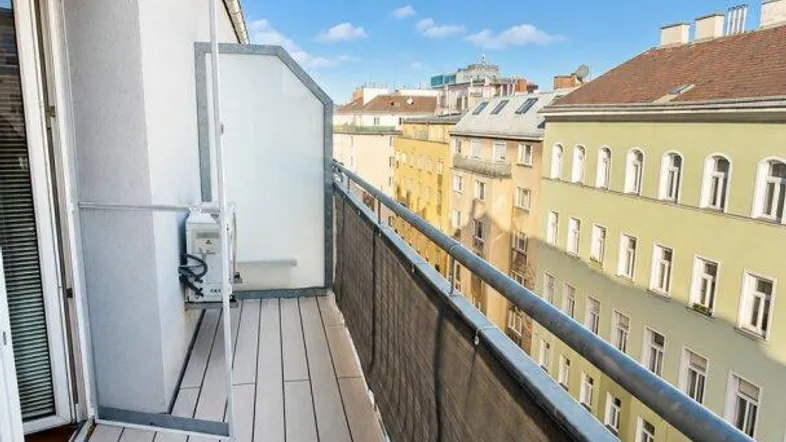 Langer Balkon mit Holzdielenboden und Blick auf die umliegenden Gebäude der Stadt.
