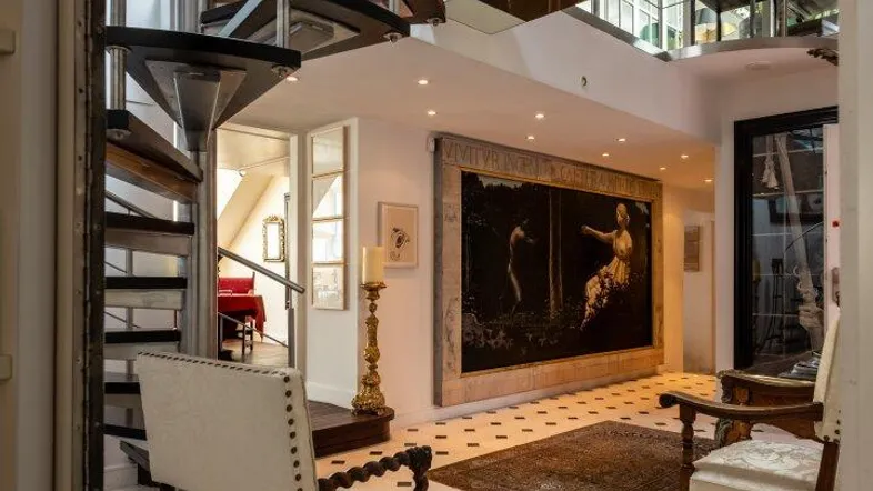 Elegante Eingangshalle mit Wendeltreppe, Schachbrettfliesen und Kunstwerken, die verschiedene Ebenen verbindet.