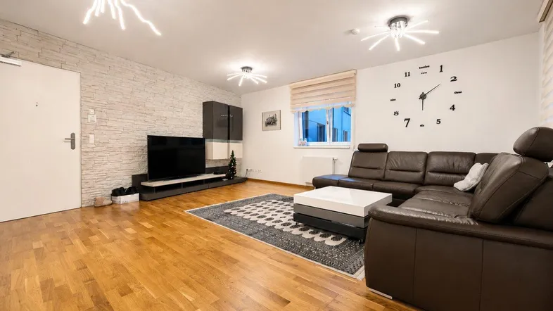 Helles Wohnzimmer mit modernem Ledersofa, Holzboden und dekorativer Steinwand.