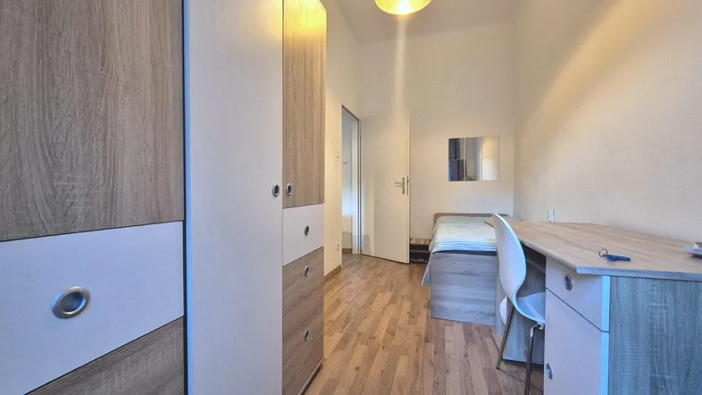 Kleines Schlafzimmer mit Bett, Schreibtisch und Kleiderschrank, ideal für Studenten oder Gäste.