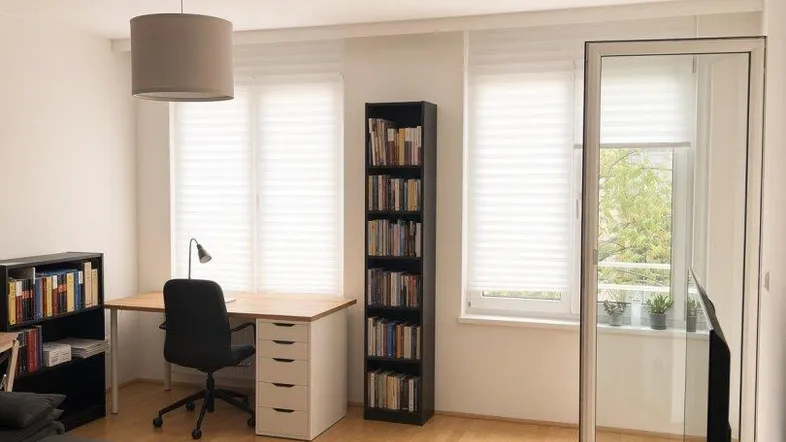 Helles Wohnzimmer mit Parkettboden, Arbeitsbereich und Zugang zu einem Balkon.