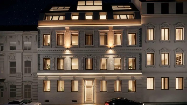 Nachtaufnahme der eleganten Fassade eines modernen Wohngebäudes mit beleuchteten Fenstern und Straßenansicht.