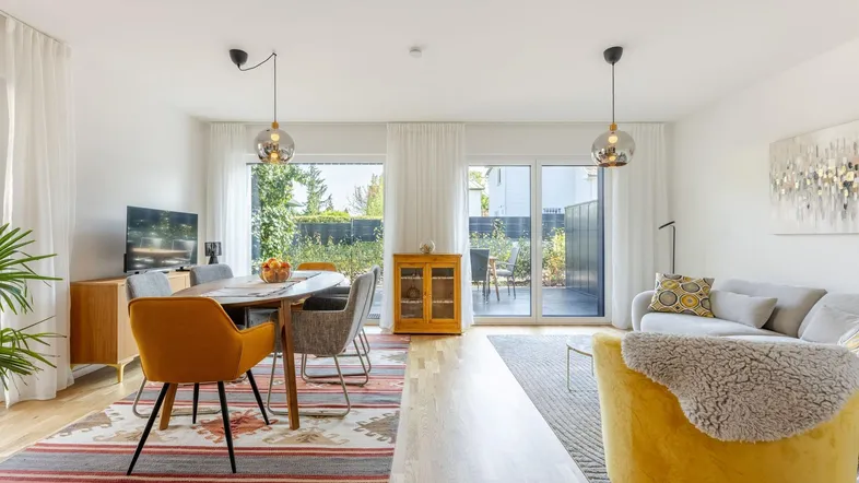 Heller offener Wohn- und Essbereich mit Holzboden, modernen Möbeln und Zugang zur Terrasse.
