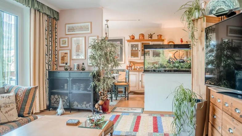 Gemütliches Wohnzimmer mit Aquarium, Holzboden und Zugang zu einem Balkon oder Terrasse.