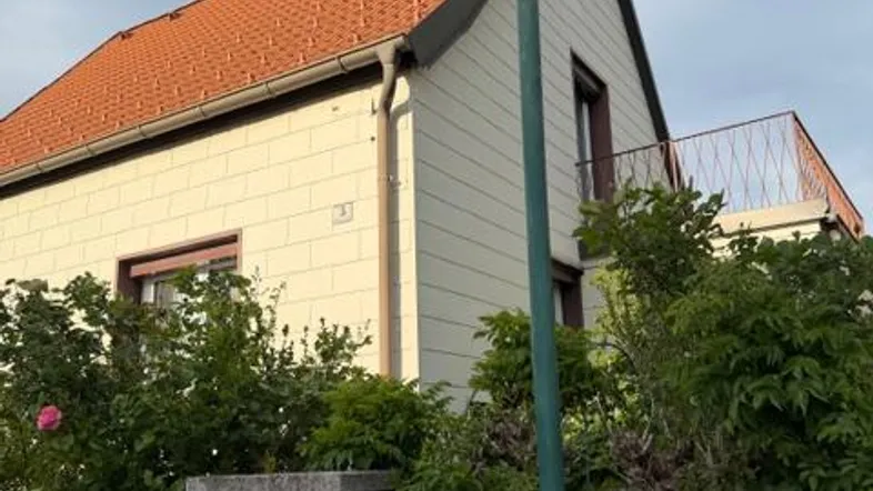 Fassade eines Einfamilienhauses mit Ziegeldach und einem kleinen Balkon im Obergeschoss.