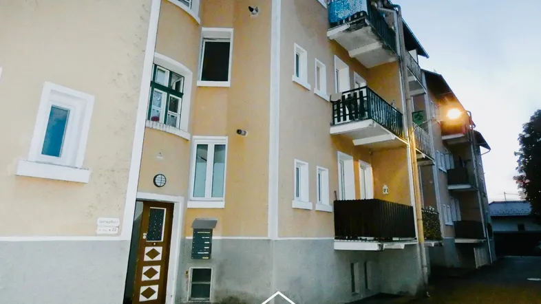 Fassade eines Mehrfamilienhauses mit mehreren Balkonen und dem Haupteingang.