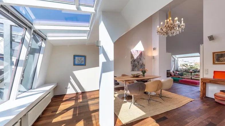 Helles und offenes Wohn-Esszimmer mit Holzboden, Dachfenstern und einem Kronleuchter.