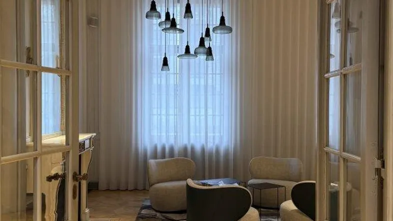 Elegantes Wohnzimmer mit Fischgrätparkett, modernen Sesseln und einer auffälligen Pendelleuchte.
