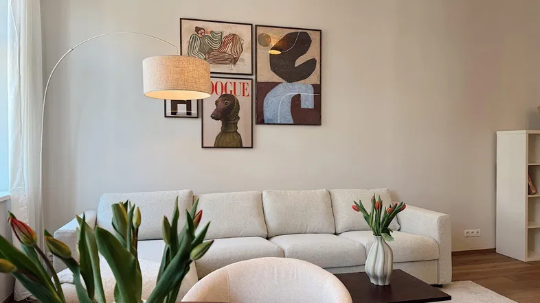 Modernes Wohnzimmer mit beigem Sofa, stilvollen Bildern und Holzboden, hell und einladend.