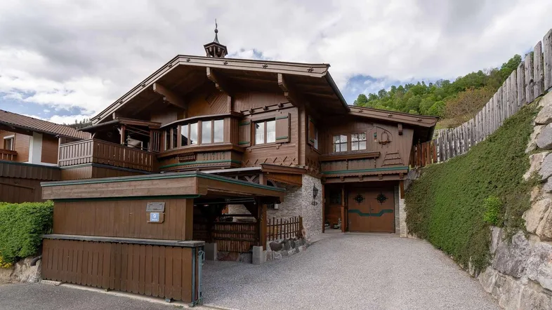 Traditionelles Holzhaus im alpinen Stil mit Garage und gepflegter Auffahrt.